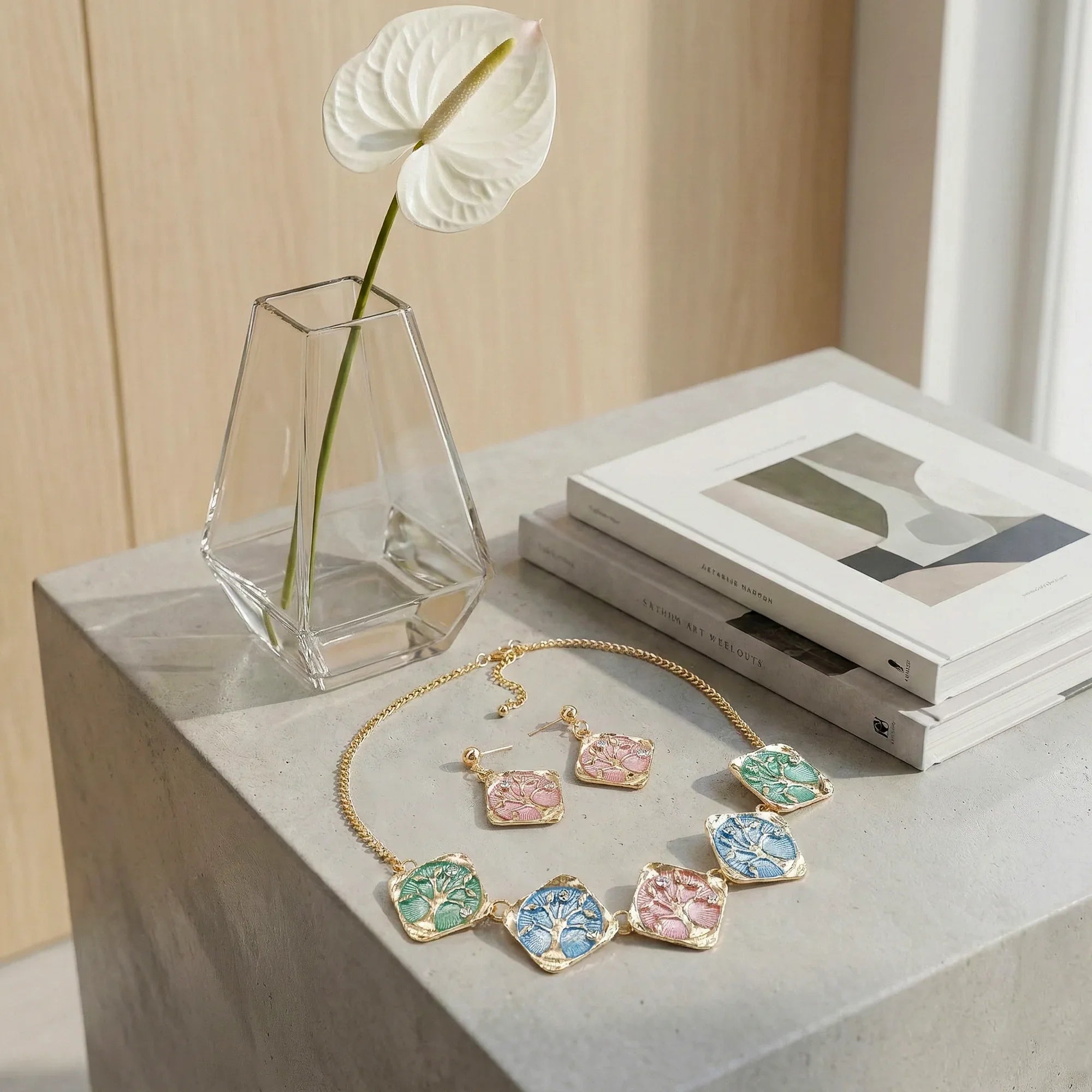 Jewelry set including a necklace and earrings on a concrete surface with a vase and books in the background.