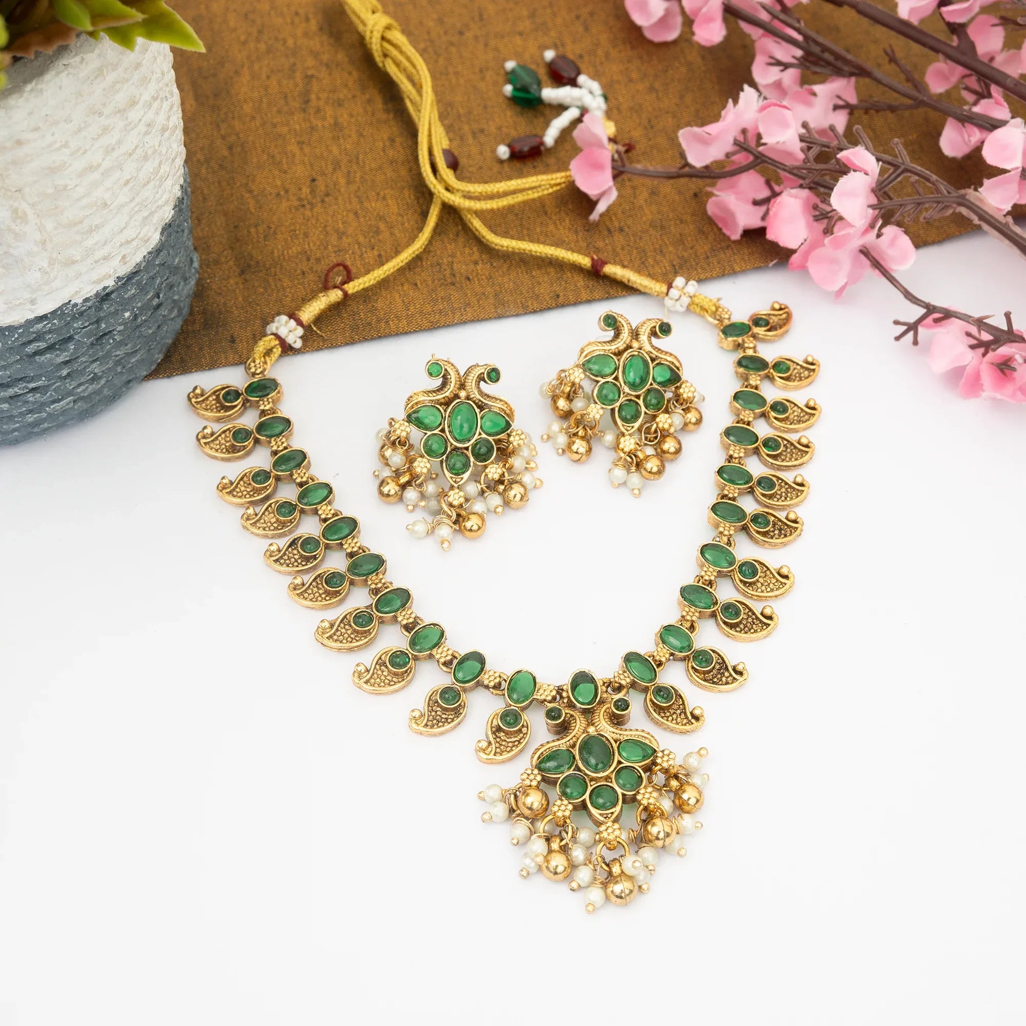 Gold and green jewelry set with flowers on a white background