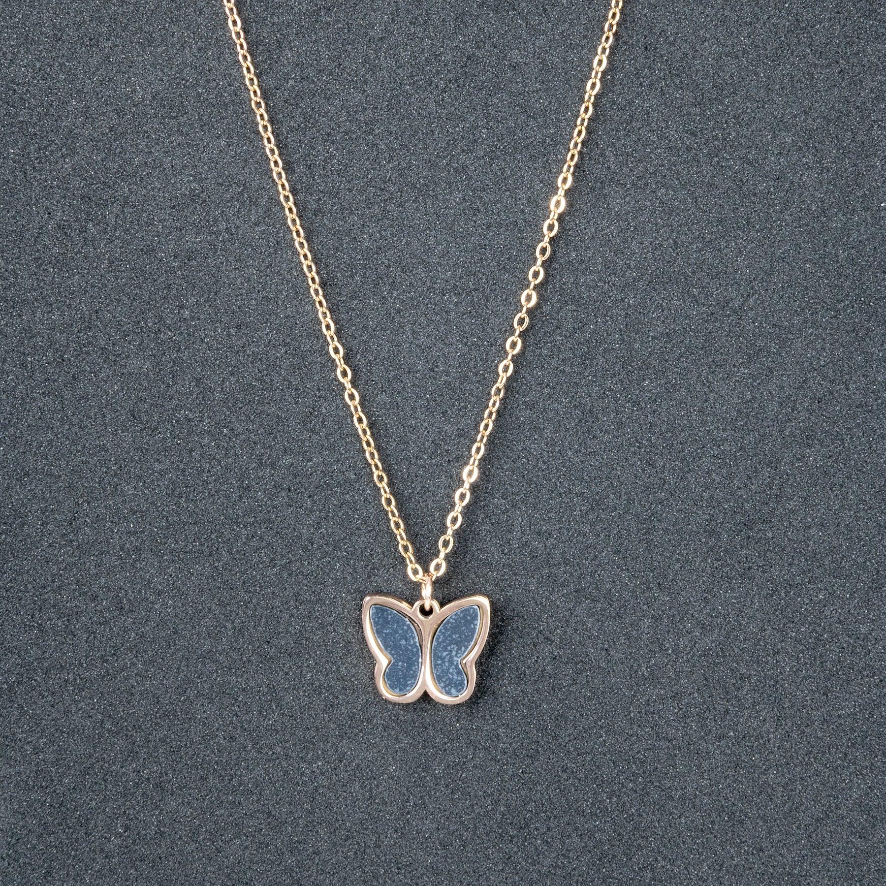 Butterfly pendant necklace on a chain against a gray background