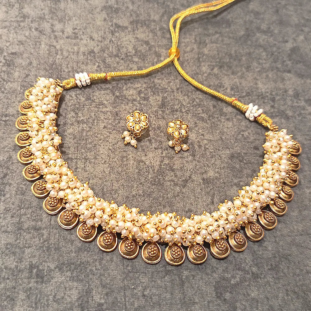 Gold and pearl necklace set on a gray surface