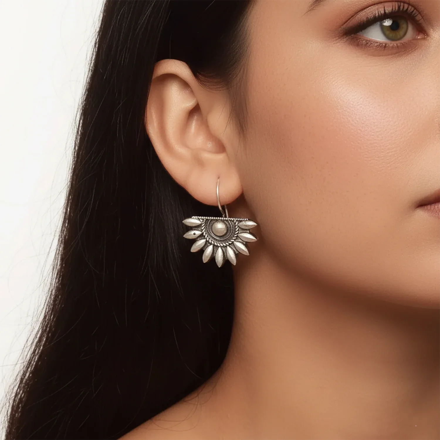 Close-up of a woman wearing a silver earring with a floral design.