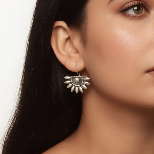 Close-up of a woman wearing a silver earring with a floral design.