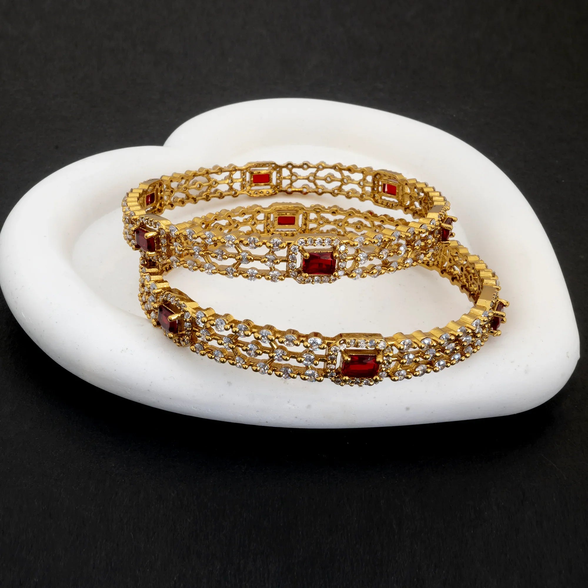 Gold bracelet with red gemstones on a white stone surface
