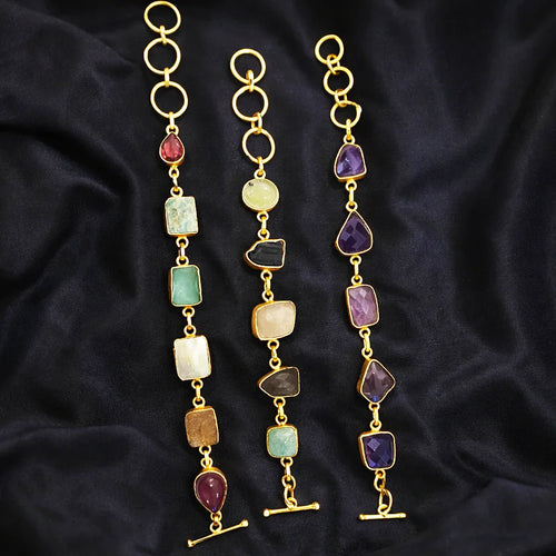 Gold necklaces with colorful gemstones on a dark fabric background
