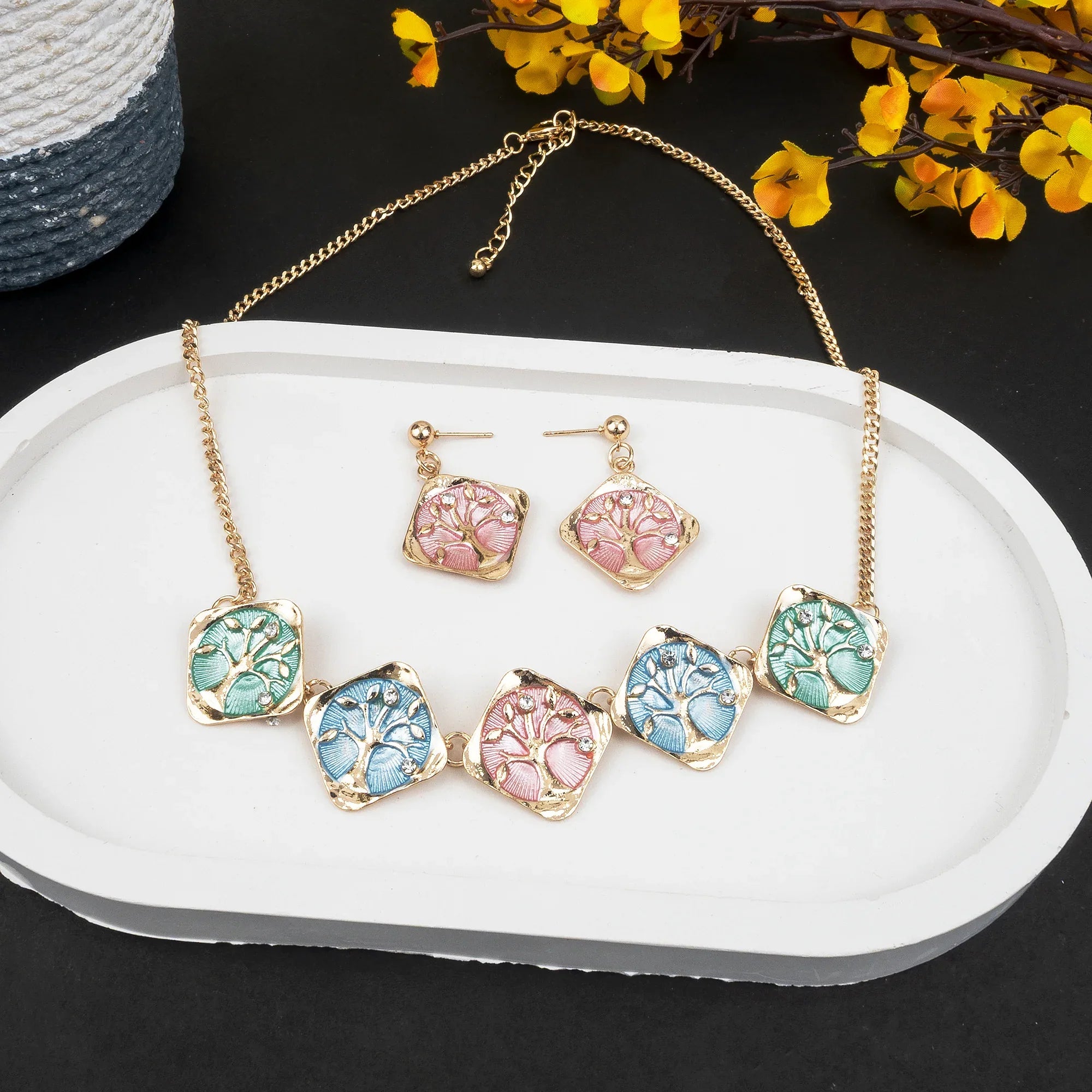 Jewelry set with necklace and earrings on a white tray with flowers in the background