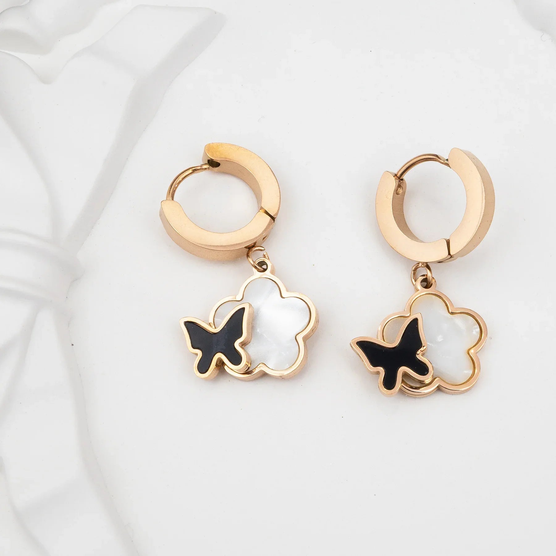 Gold hoop earrings with butterfly charms on a white background