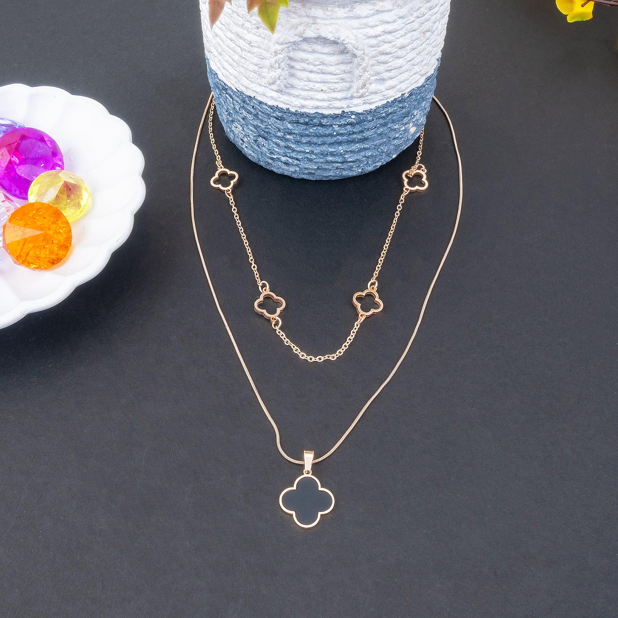 Gold necklace with clover pendants on a dark surface
