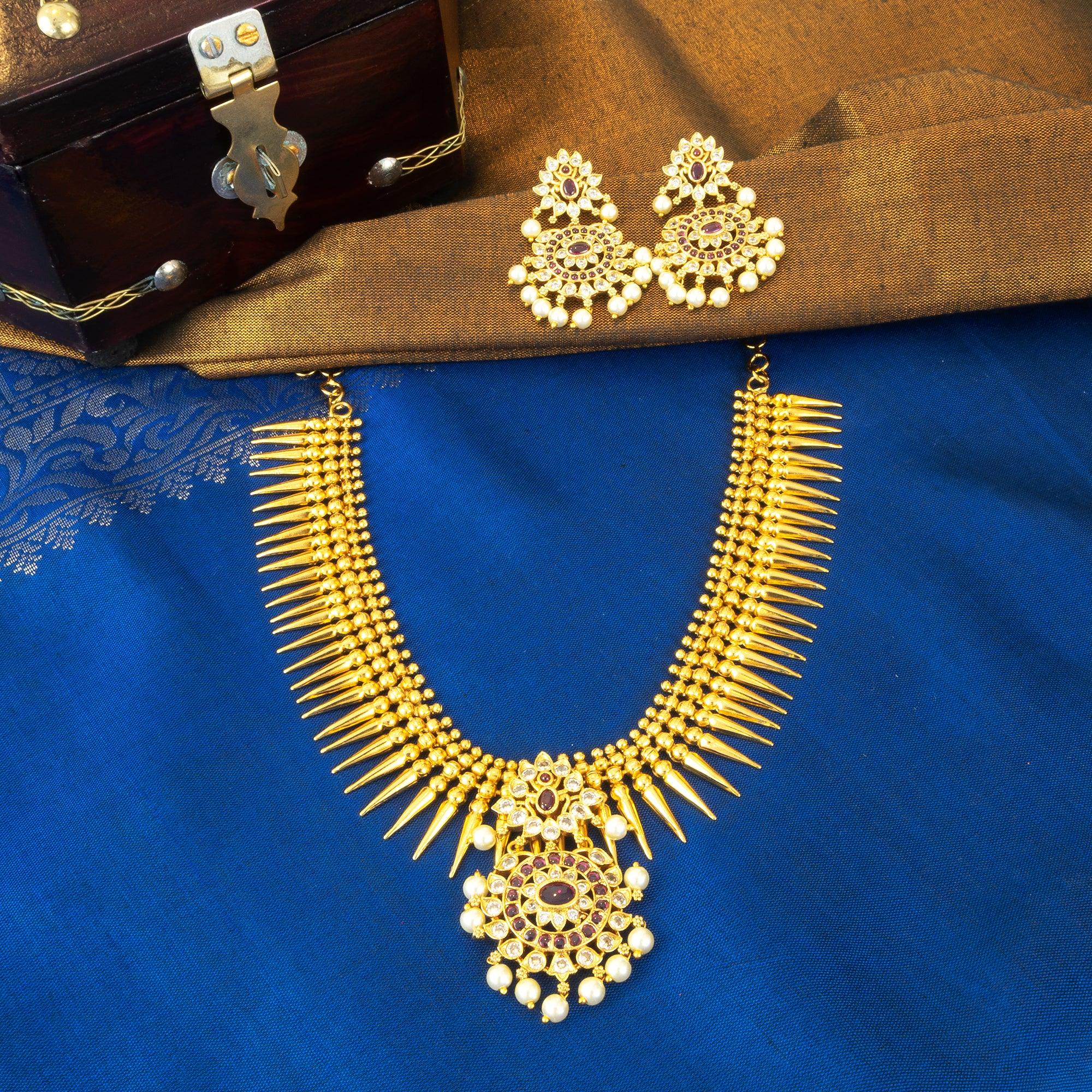 Gold necklace and earrings on a blue fabric background