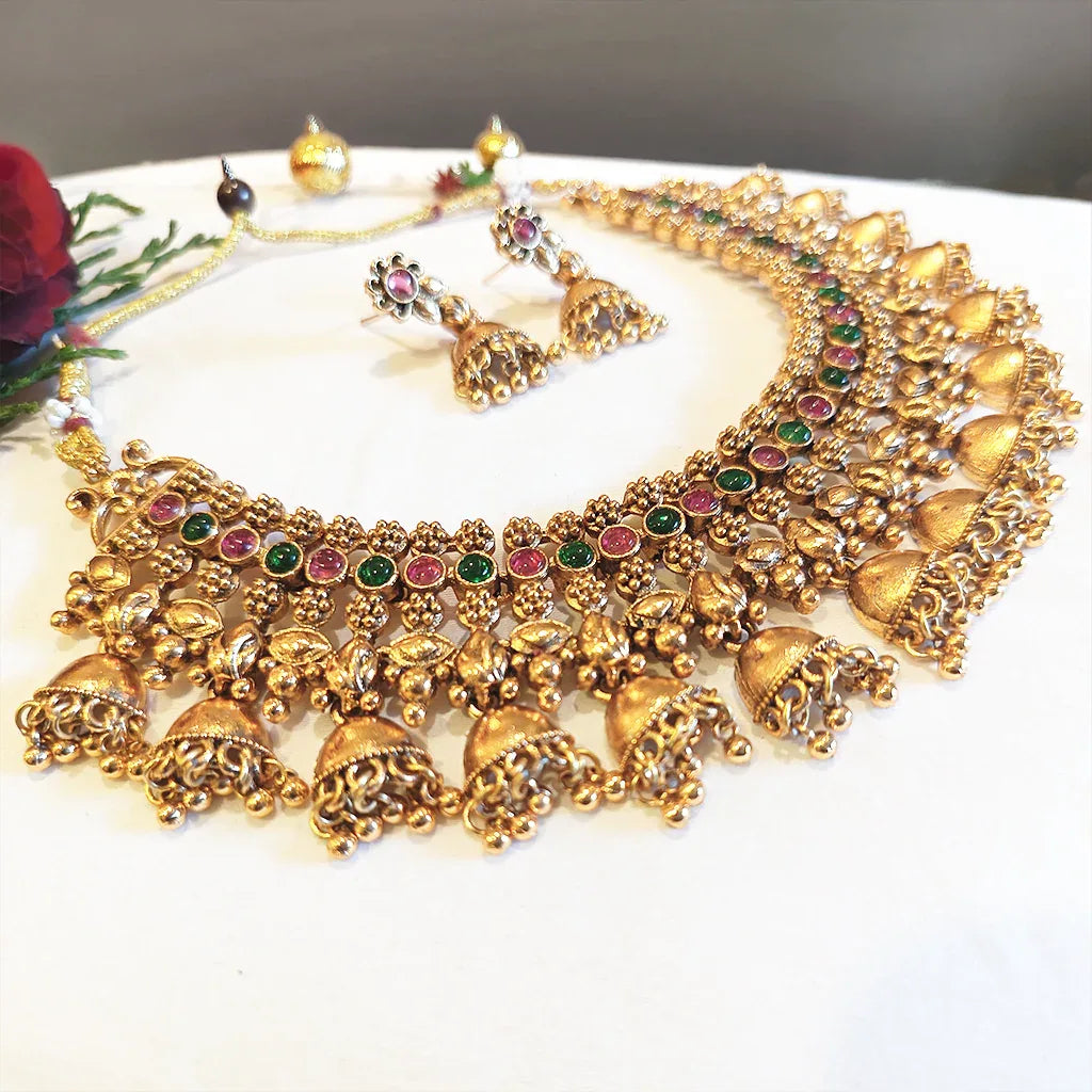 Gold necklace with gemstones on a white surface