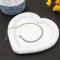 Gold bracelet with blue stones on a white stone surface with a dark background