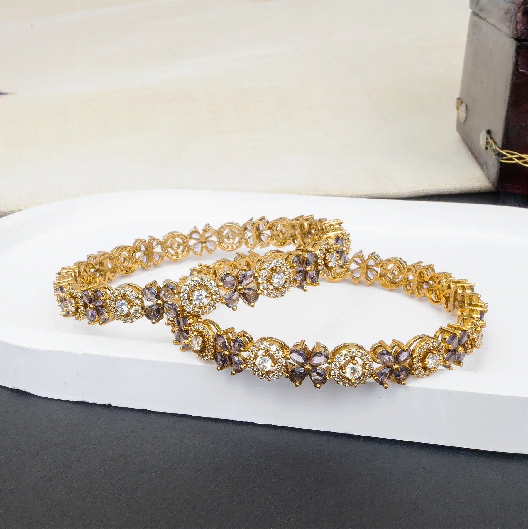 Gold bracelet with gemstones on a white surface