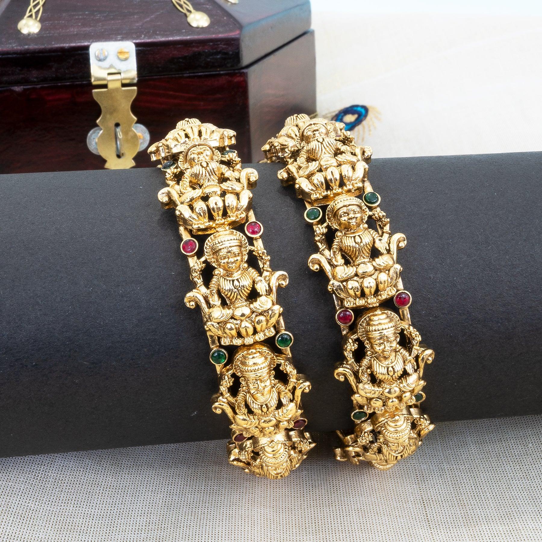 Gold earrings with intricate designs on a black surface