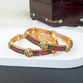 Gold bangles with colorful stones on a white surface