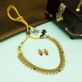 Gold necklace with red stones and matching earrings on a light green surface.