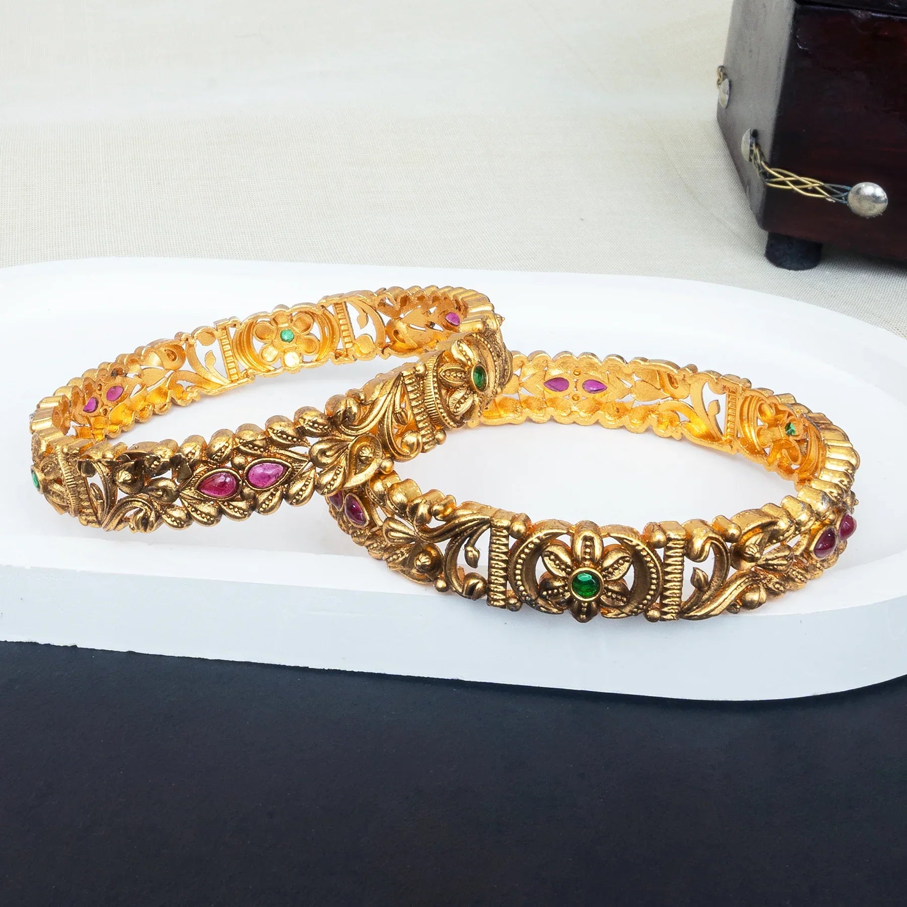 Gold bracelet with gemstones on a white surface