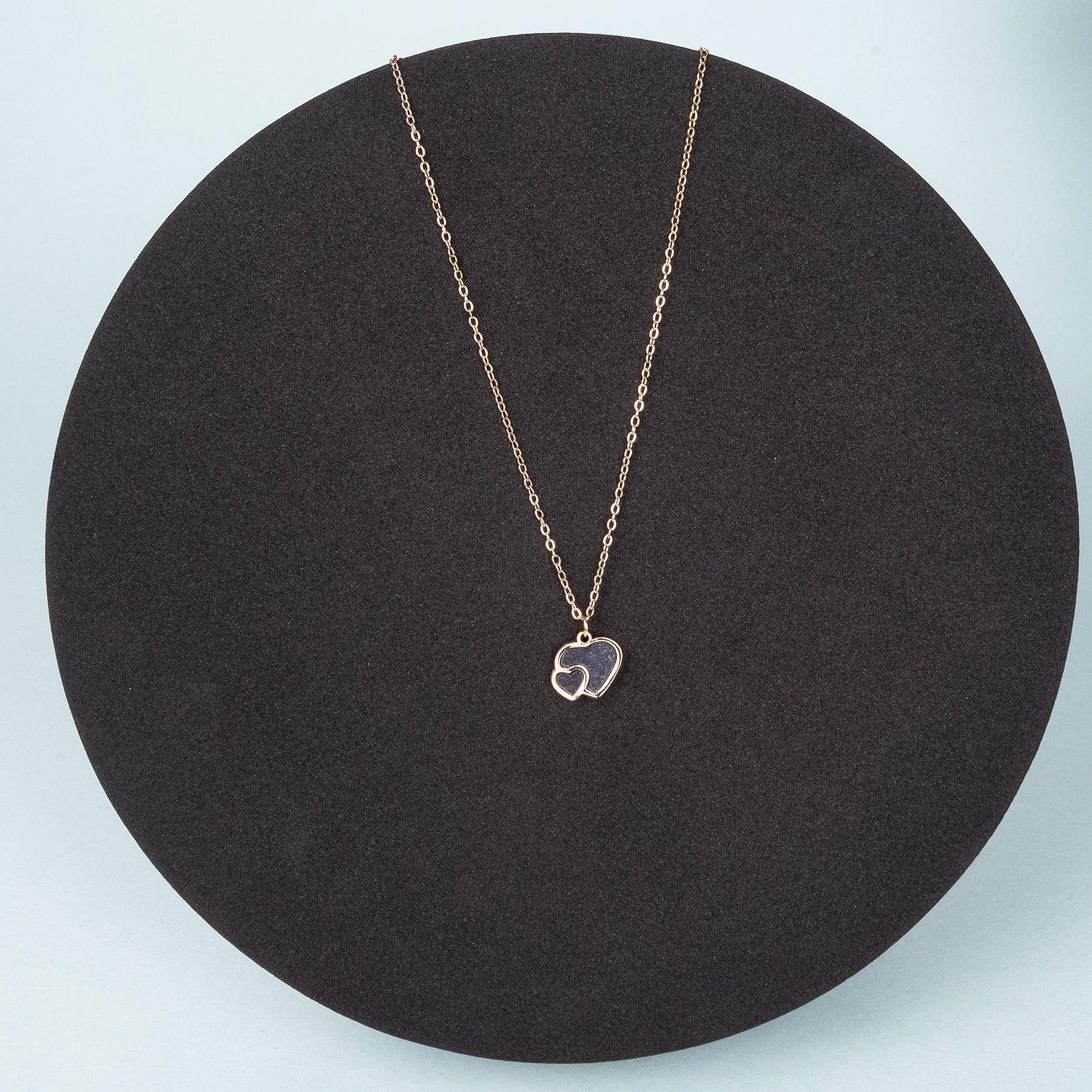 Necklace with a heart-shaped pendant on a black stand against a light blue background