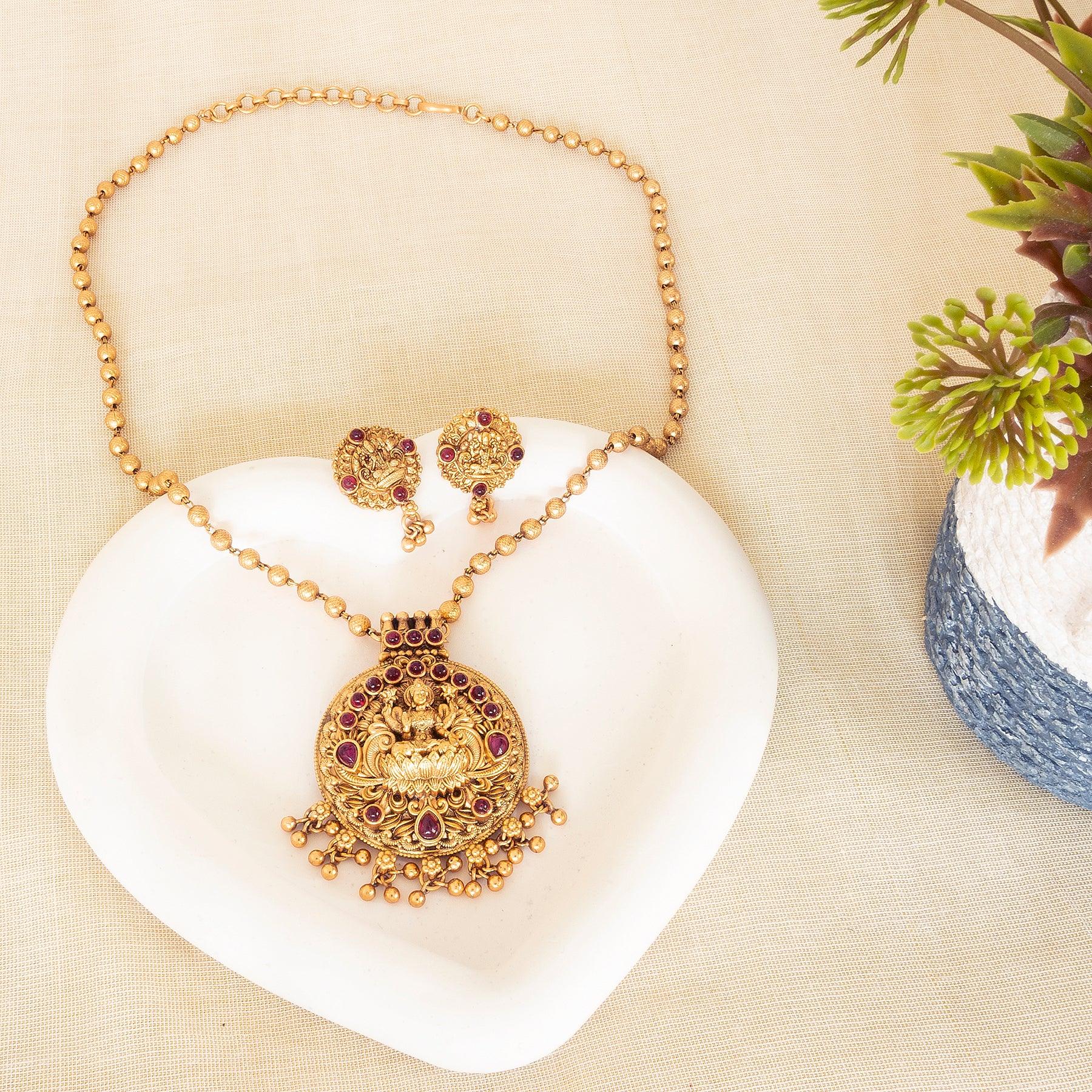 Gold necklace and earrings set on a white shell with a natural background