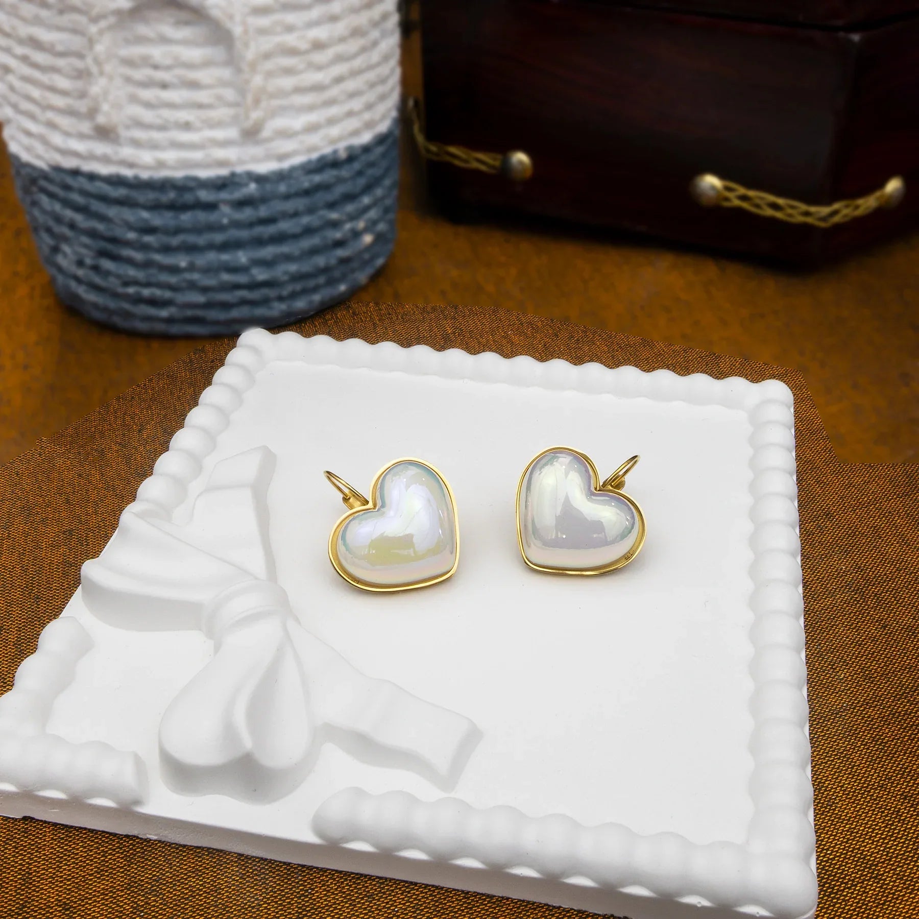 Heart-shaped earrings with gold frames on a white textured stand.