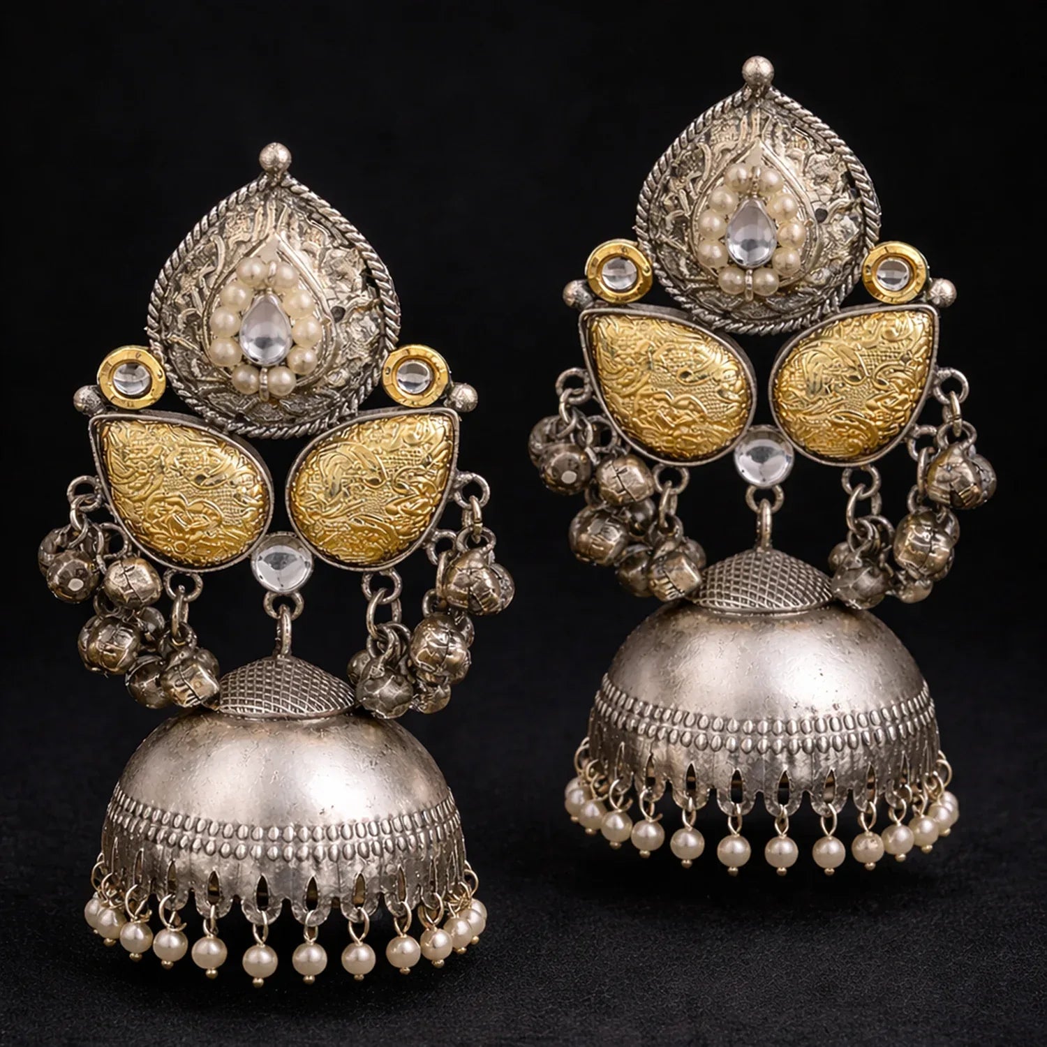 Pair of ornate silver and gold earrings with pearl-like beads on a black background