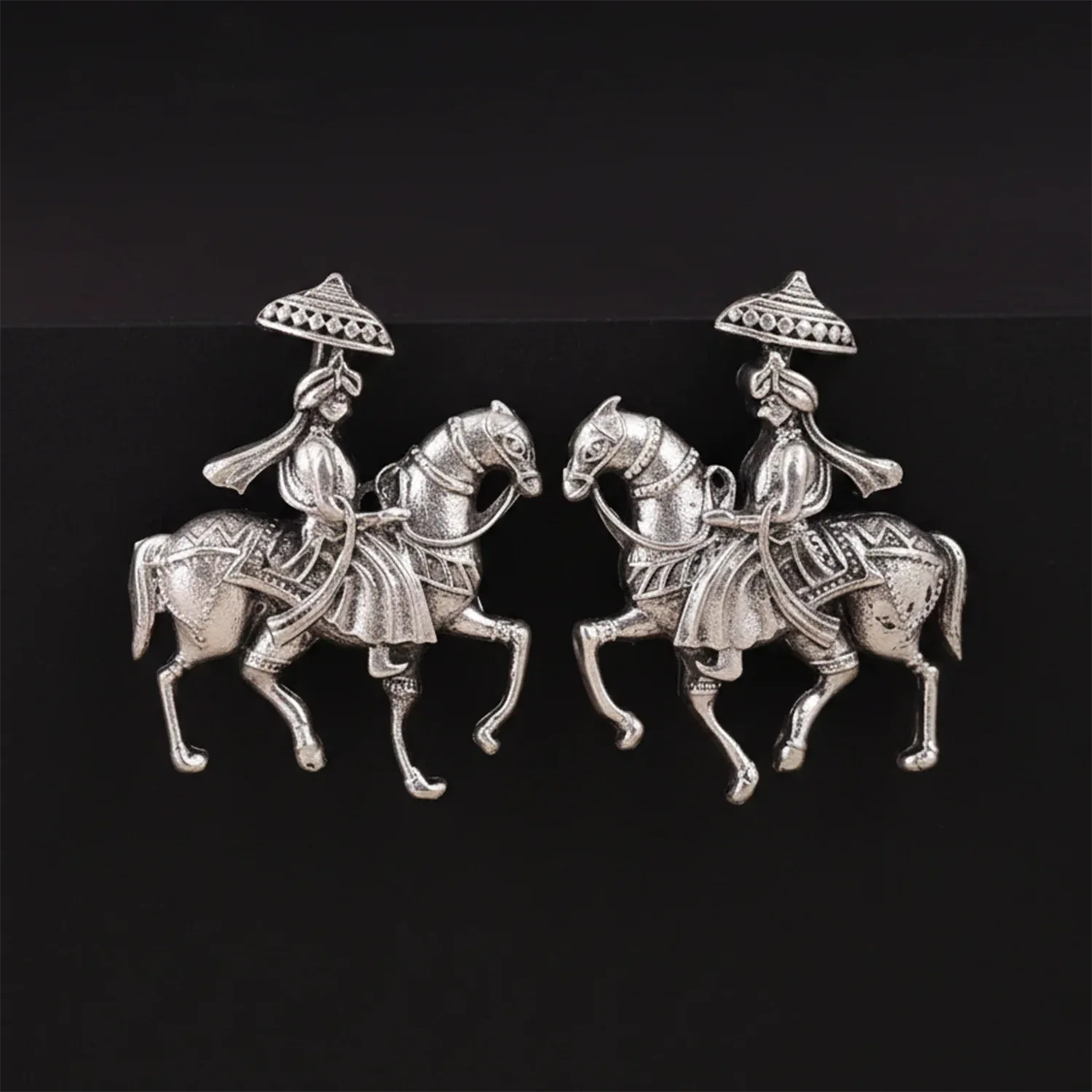 Pair of silver horseback riders with hats on a black background