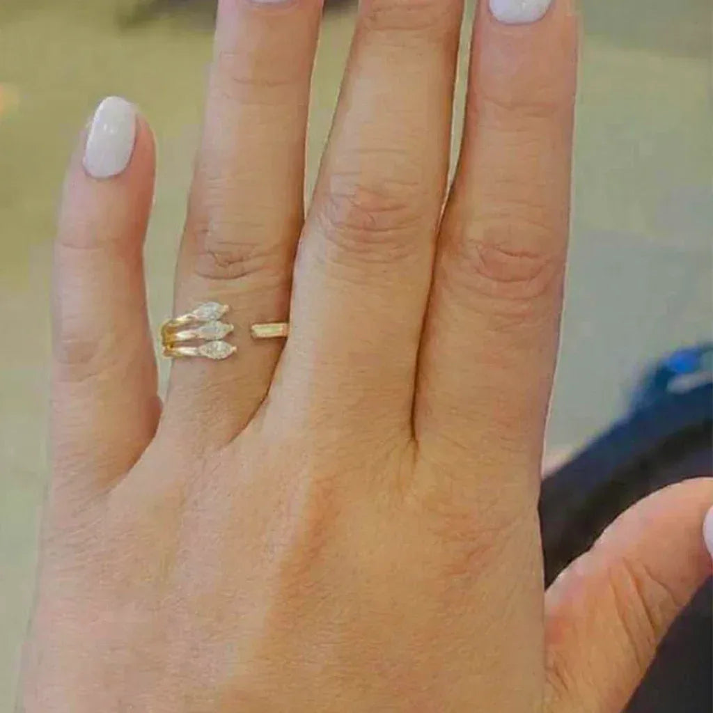 Gold ring with marquise-shaped gemstones on a person's finger.