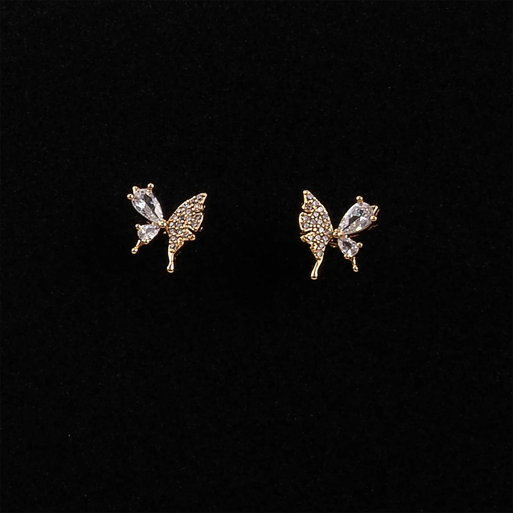 Butterfly-shaped earrings with gemstones on a black background