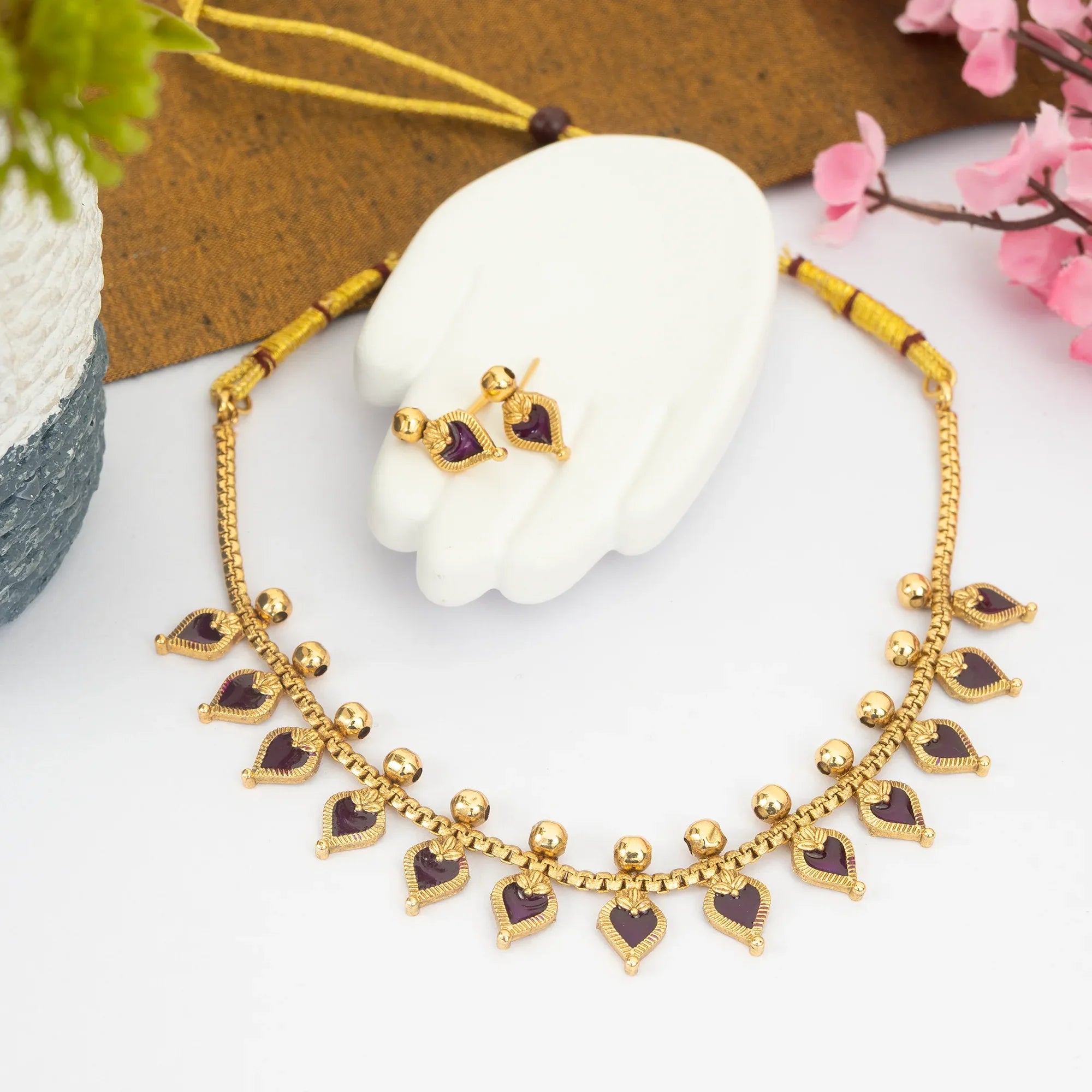 Gold necklace with heart-shaped pendants on a white surface with decorative elements.