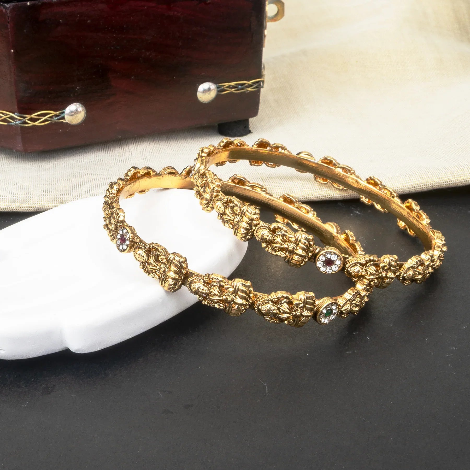 Gold bracelets with decorative elements on a dark surface