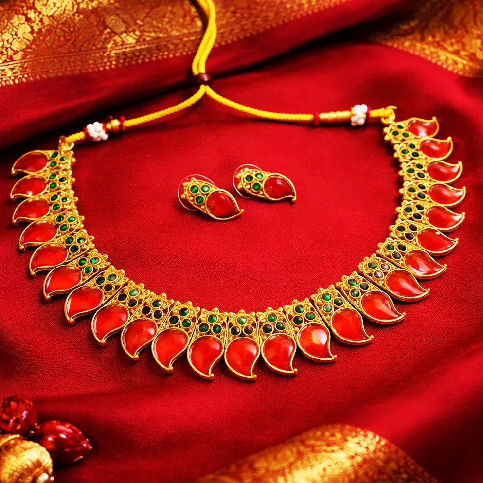 Ornate necklace with red stones and green accents on a red fabric background