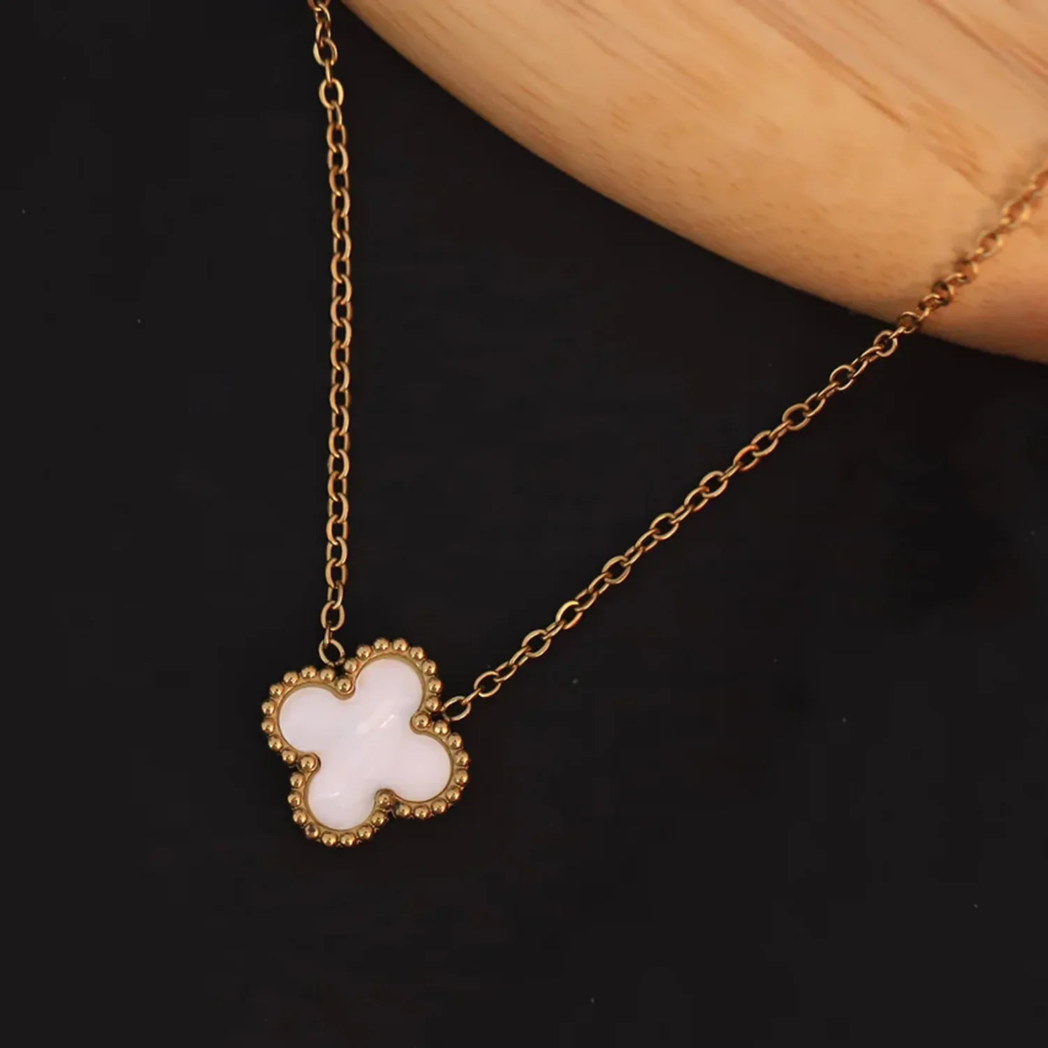 Gold necklace with a white flower pendant on a dark background