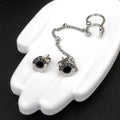 Silver earrings with black stones on a white hand model against a black background