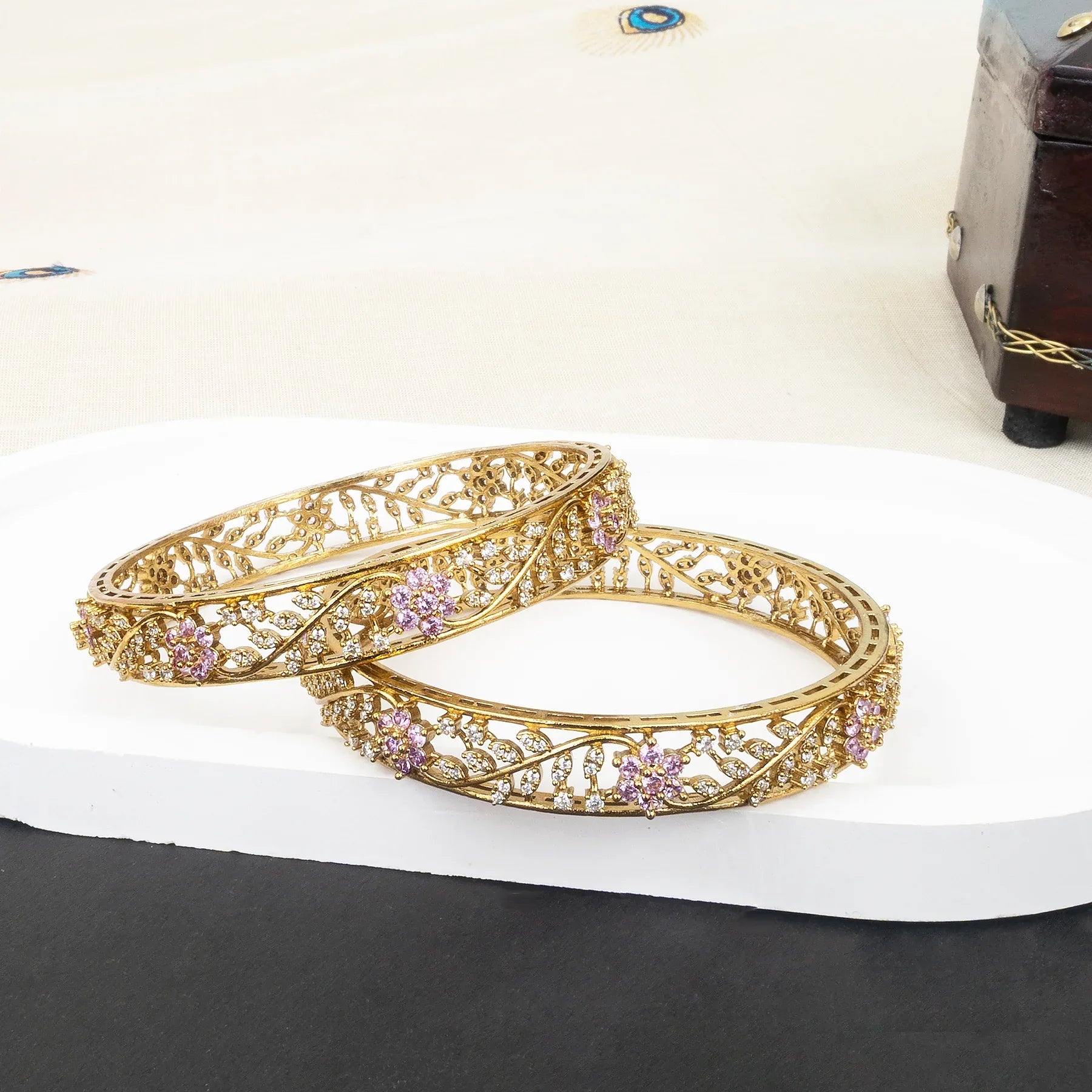 Gold bangles with floral designs on a white surface
