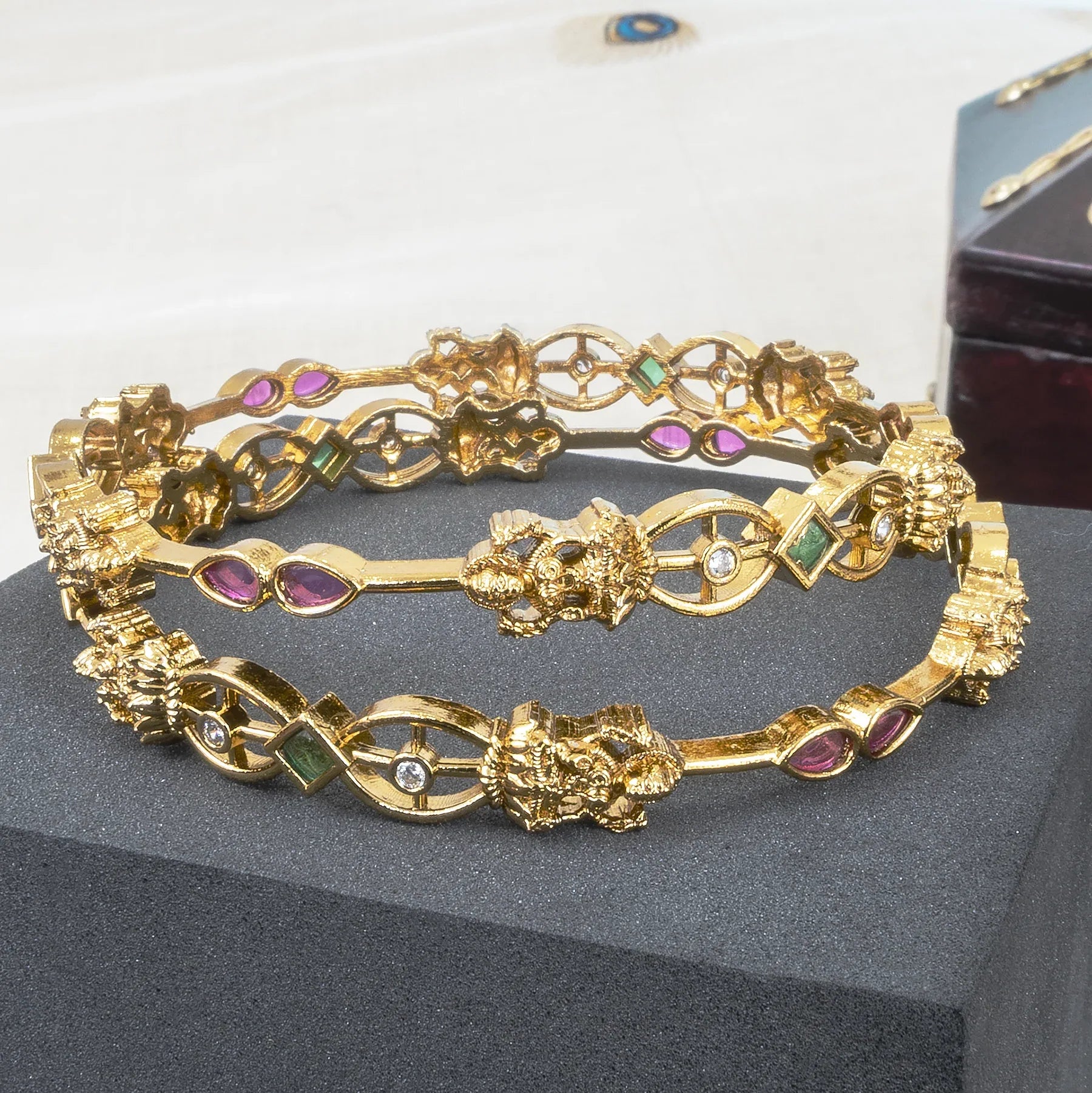 Gold bracelet with gemstones on a gray surface