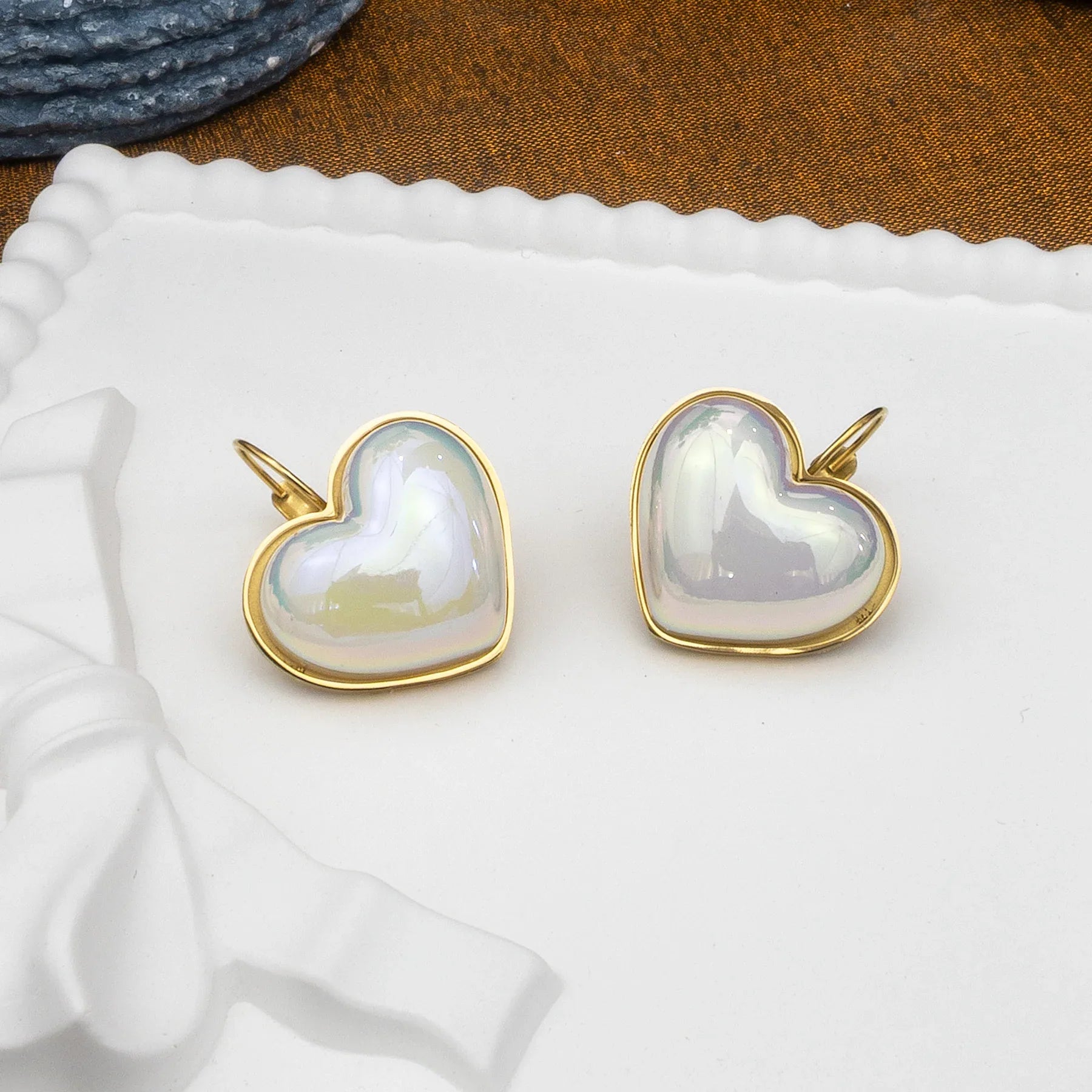 Heart-shaped earrings with gold rims on a white fabric background