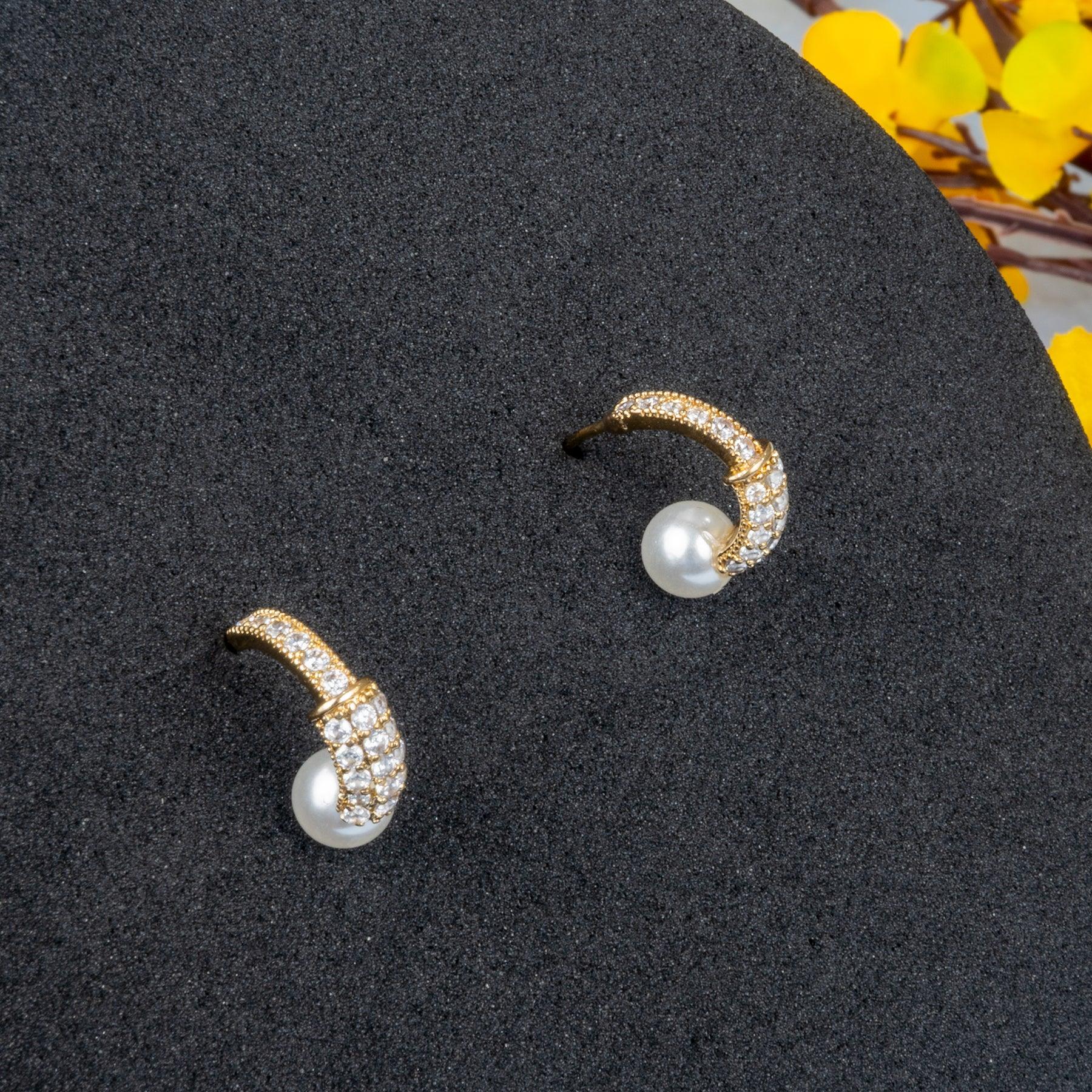 Pair of pearl earrings with gold accents on a dark surface.