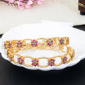 Gold bracelets with gemstones on a white plate