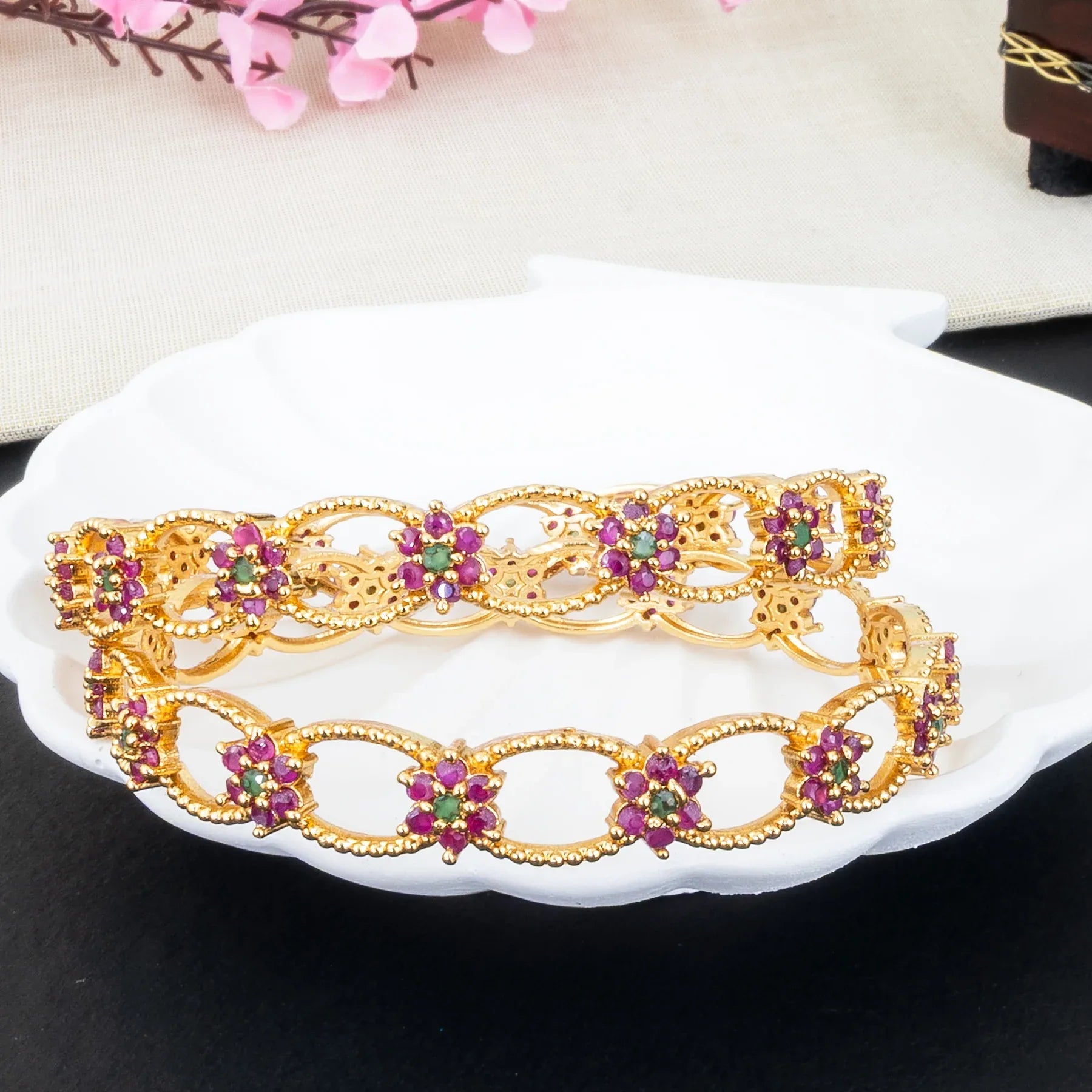 Gold bracelets with gemstones on a white plate