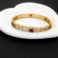 Gold bracelet with red gemstones on a white surface