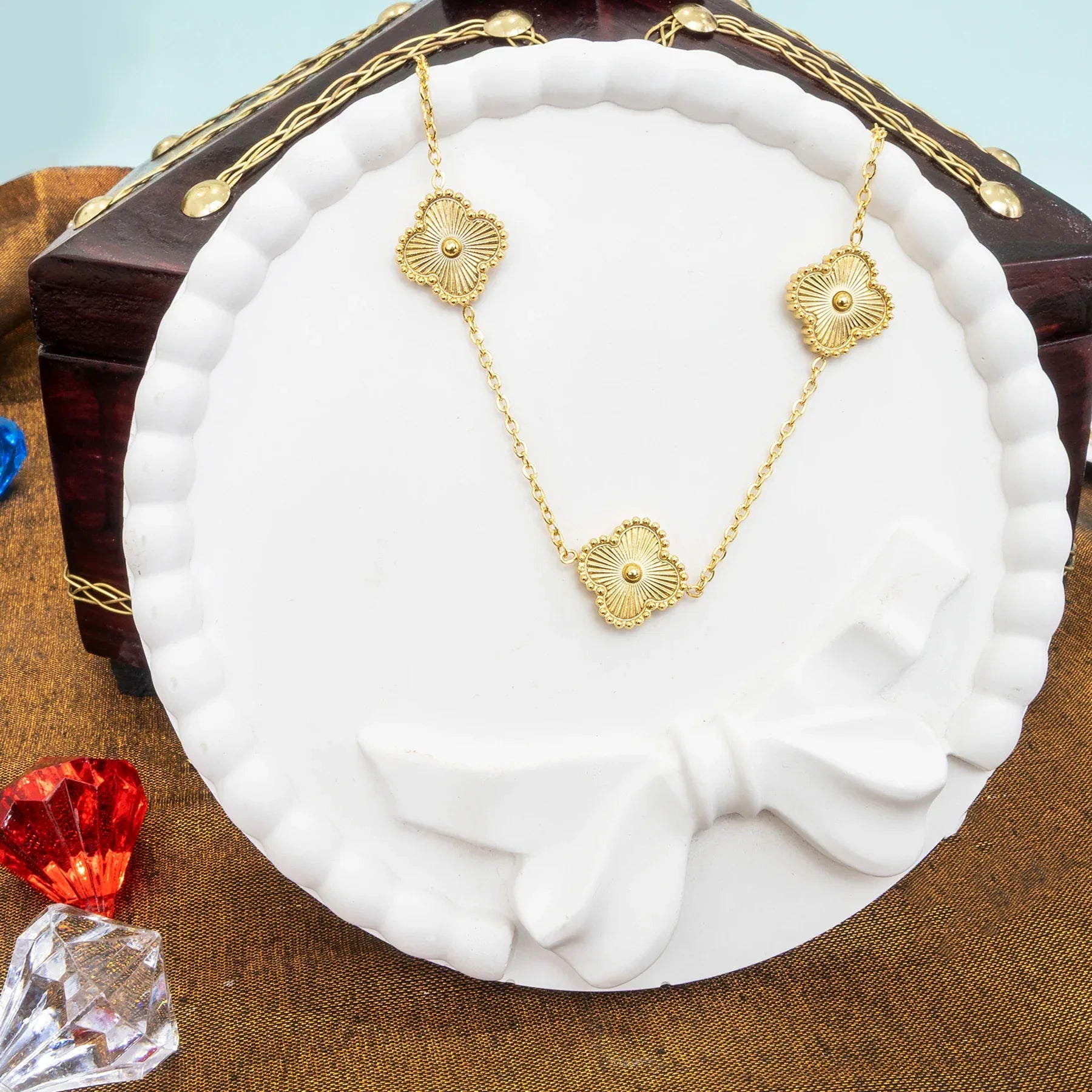 Gold necklace on a white stand with a decorative background