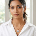 Woman wearing a white shirt and a necklace with a pendant indoors