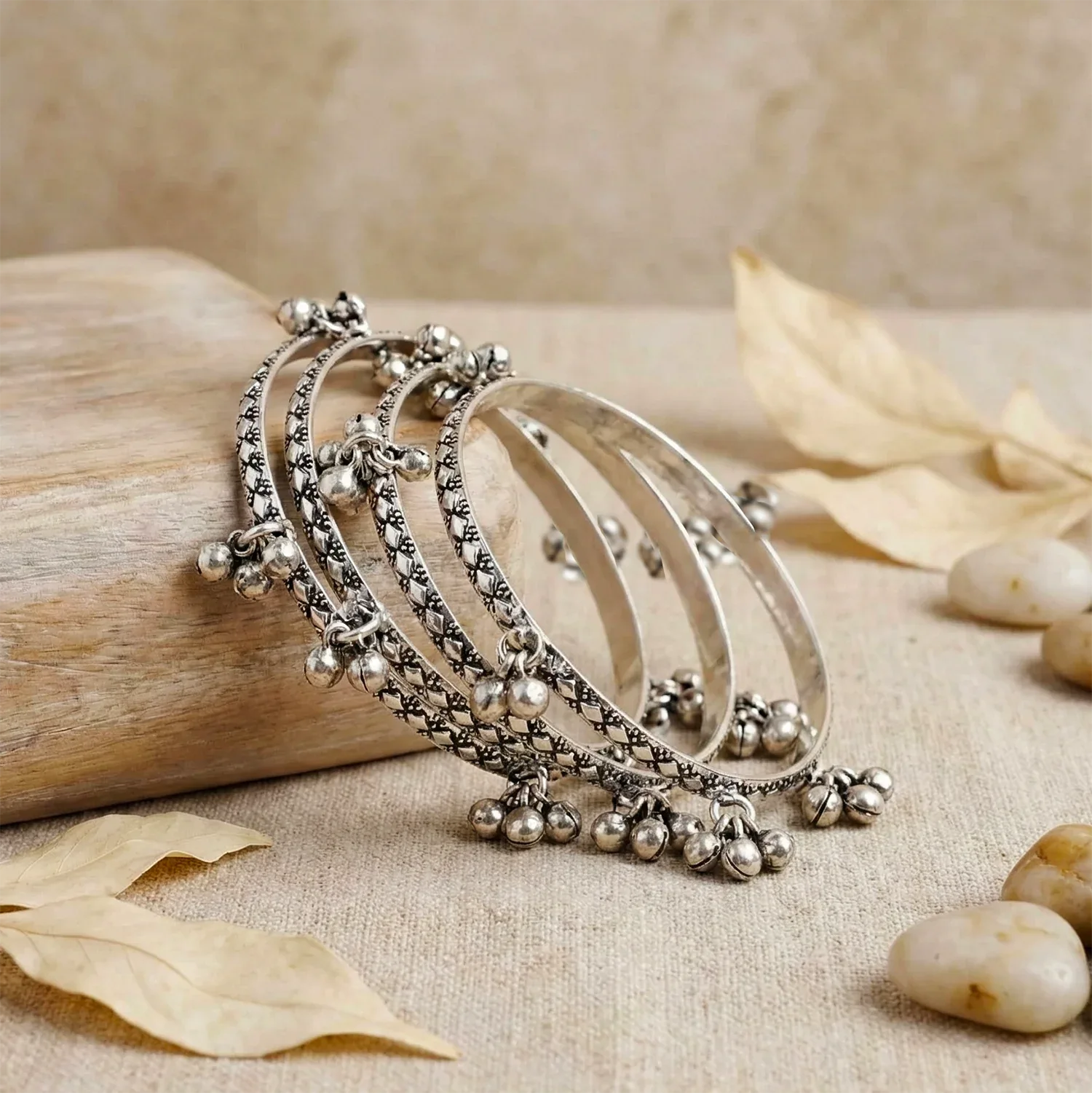Set of silver bangles on a natural wooden and stone background