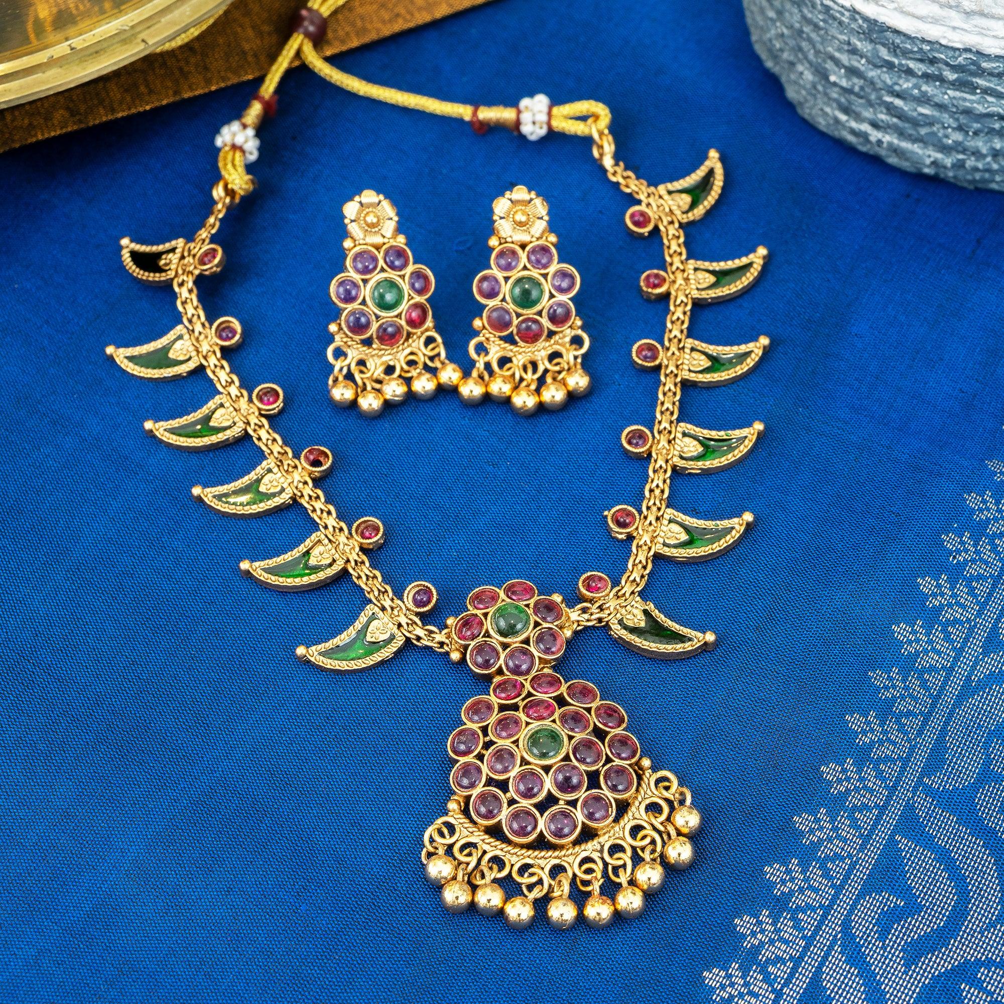 Gold necklace and earrings set on a blue fabric background