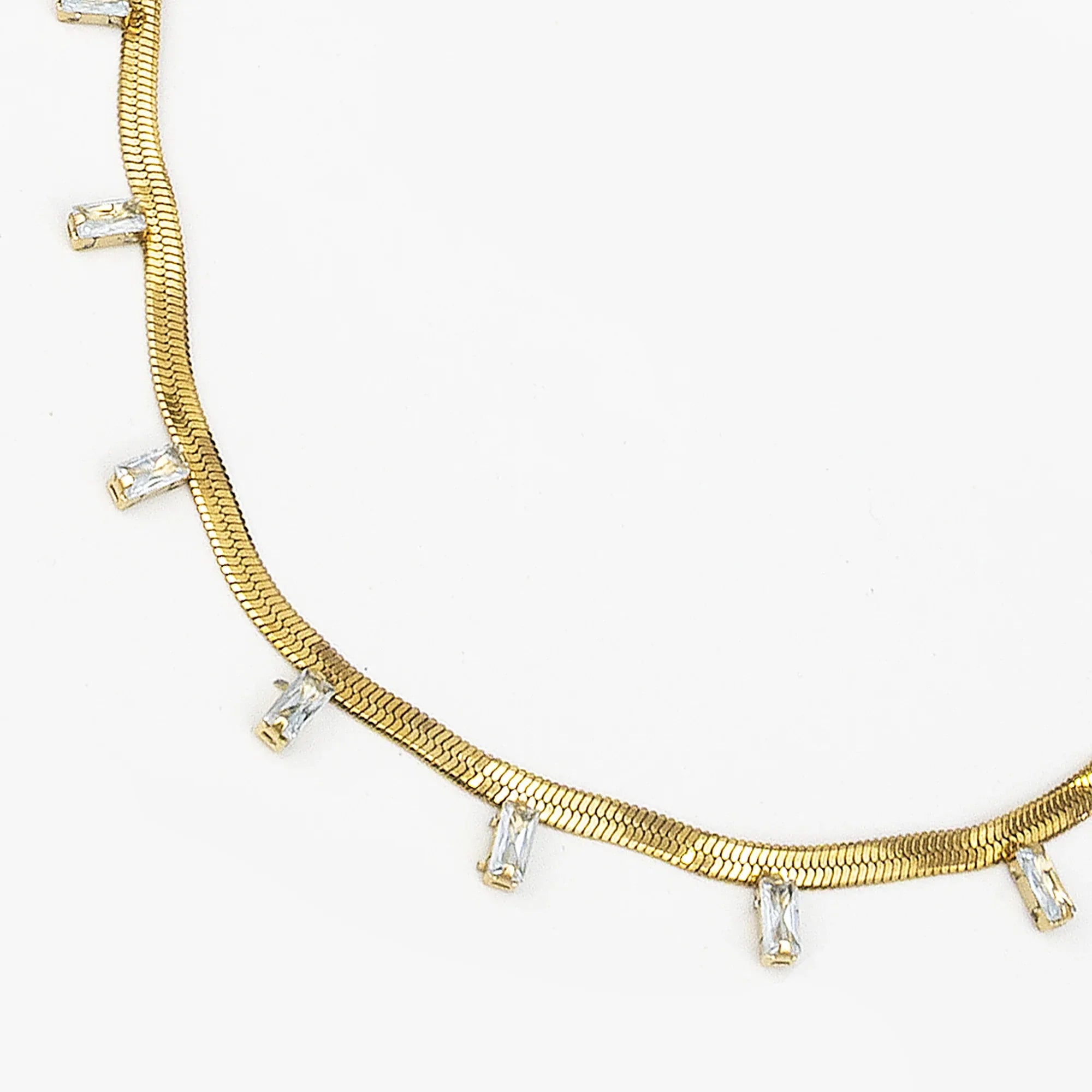 Gold necklace with clear gemstones on a white background