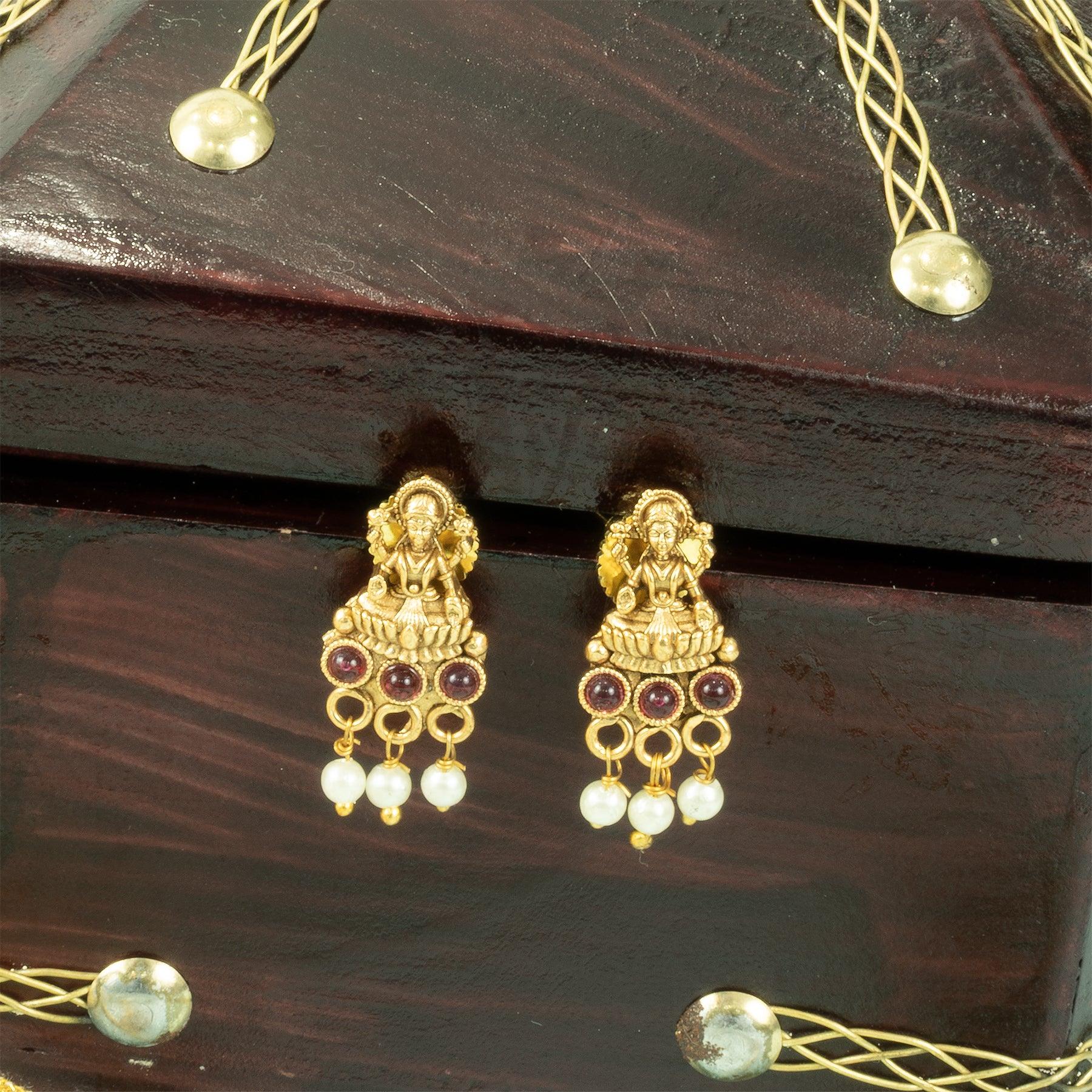 Gold earrings with purple stones on a wooden box
