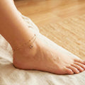 Ankle with a delicate gold anklet on a soft fabric background