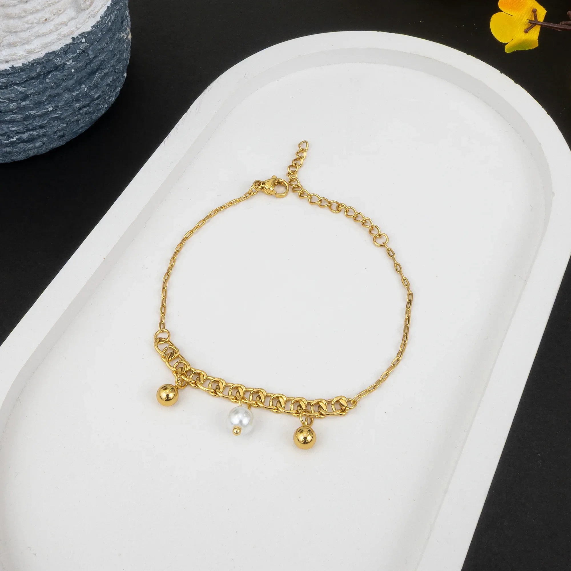 Gold bracelet with beads on a white tray