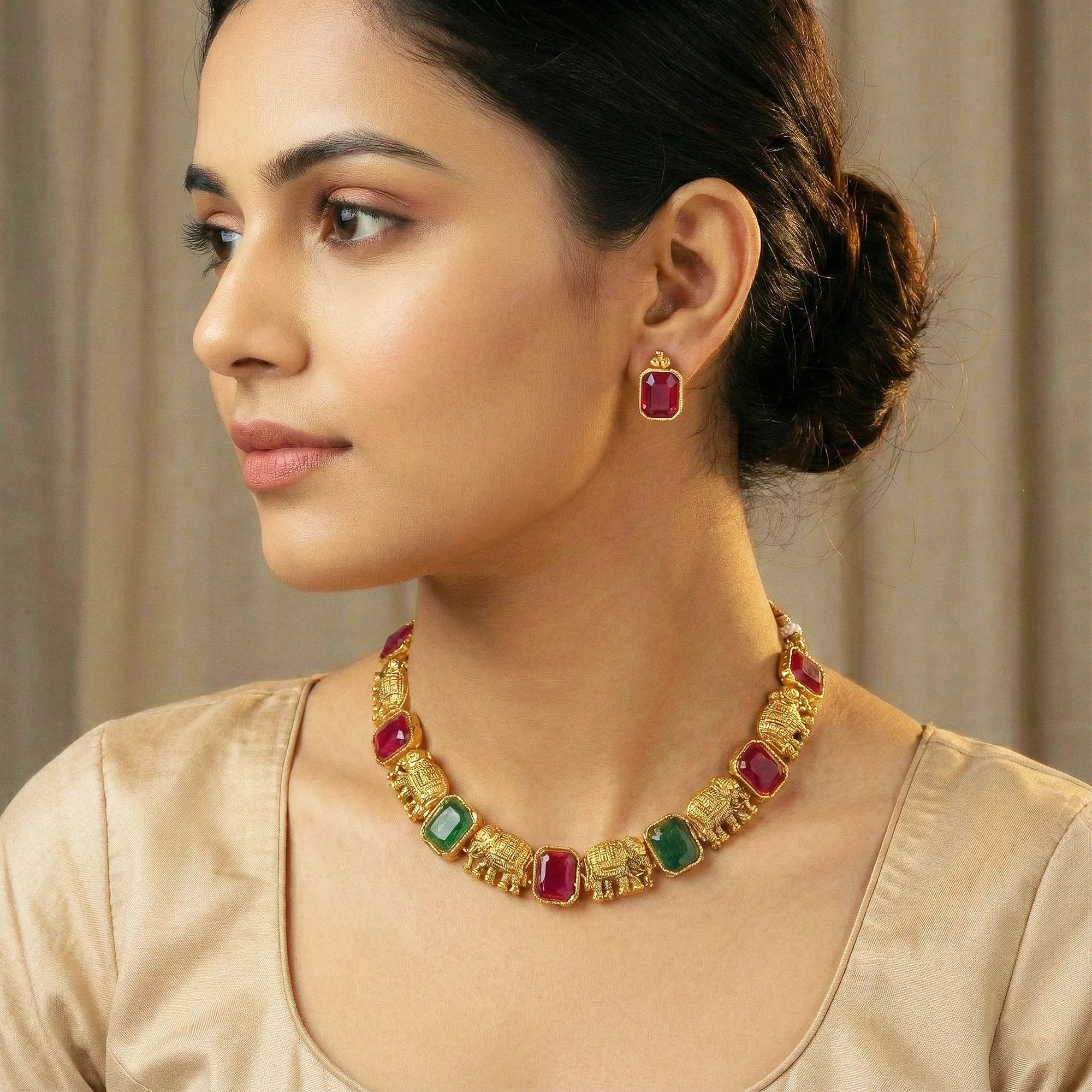 Woman wearing a gold necklace with gemstones and matching earrings.