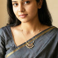 Woman wearing a traditional saree with a necklace against a beige background