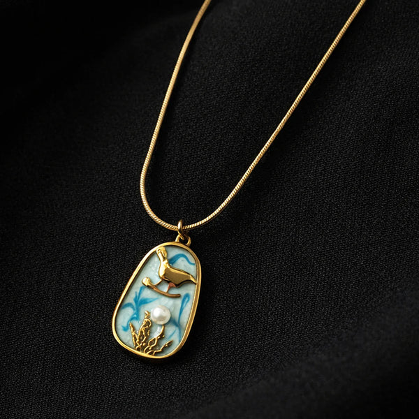 Gold necklace with a pendant featuring a deer and pearl on a black background