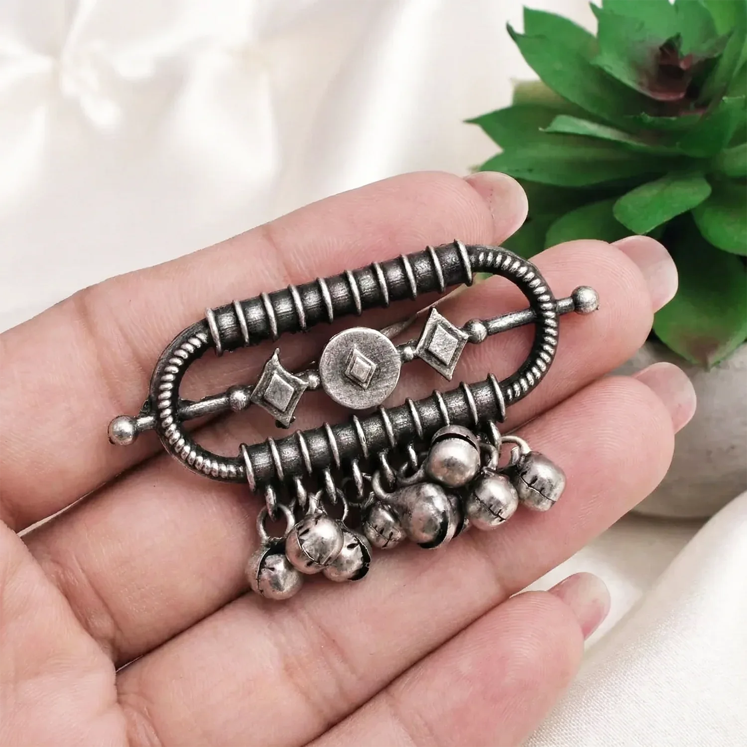 Silver bracelet with charms held in a hand against a neutral background